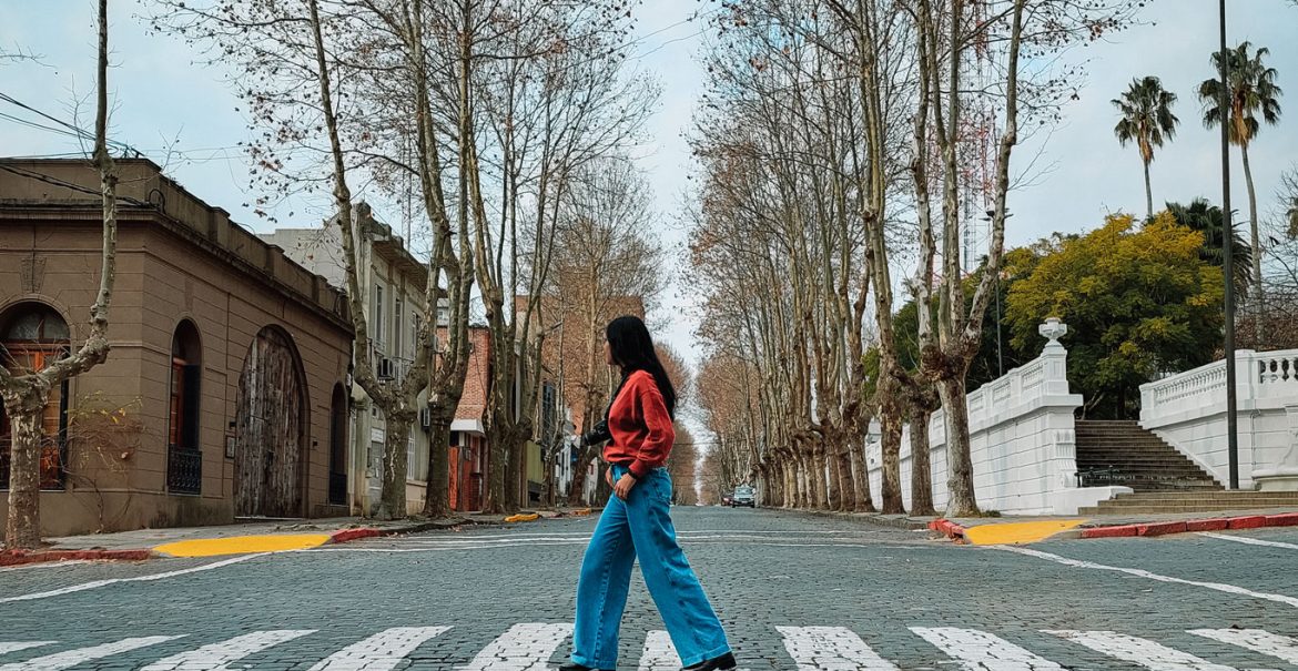 Uma mulher atravessando uma faixa em uma rua de paralelepípedos no Centro Histórico de Colonia del Sacramento.