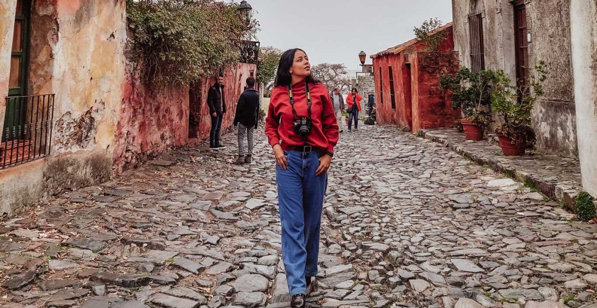 Uma mulher explorando a Calle de los Suspiros, uma atração imperdível para visitar em Colonia del Sacramento em um dia.