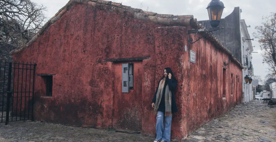 Foto de uma mulher diante da construção avermelhada do Museu Casa Portuguesa.