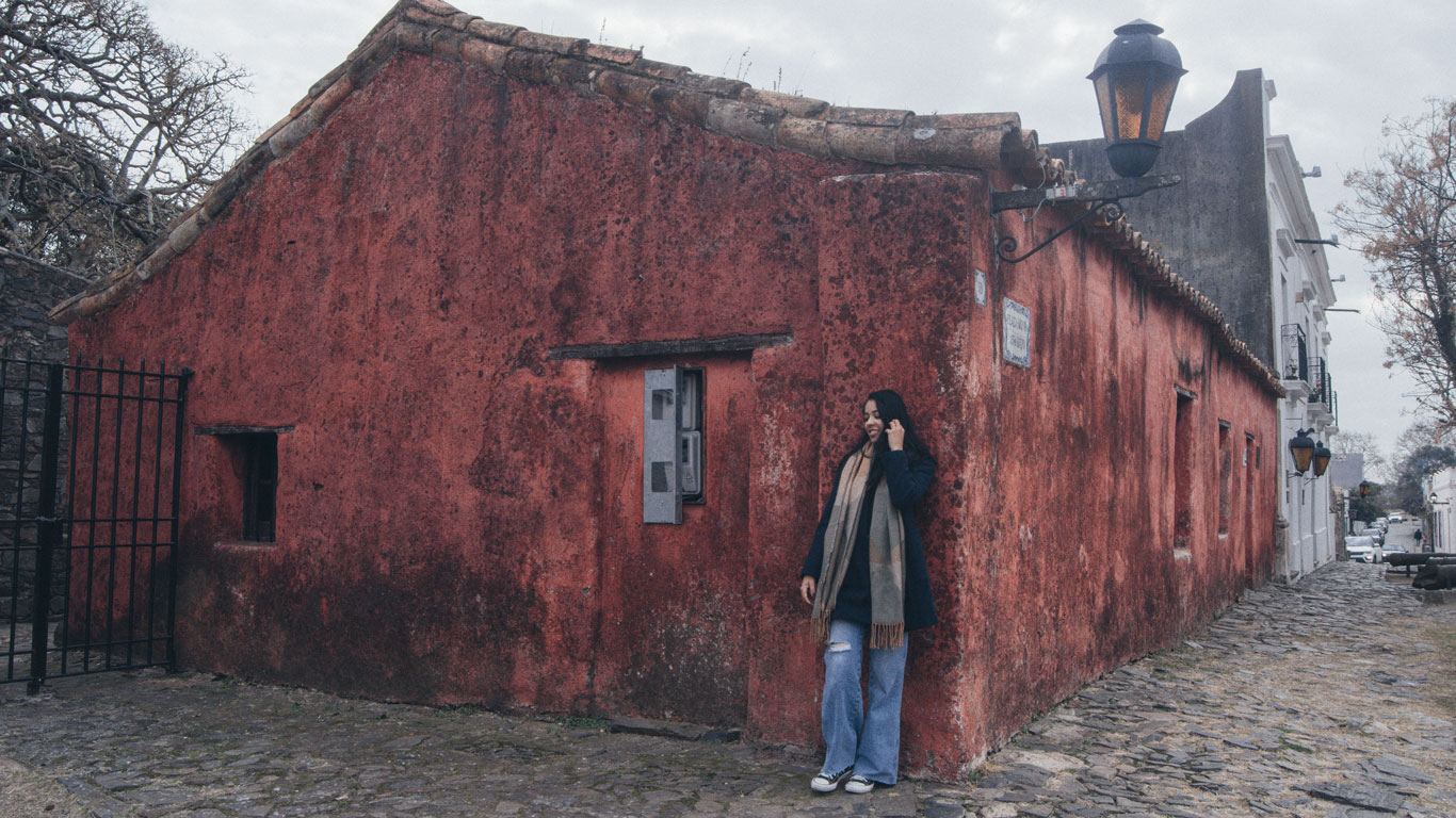 Foto de uma mulher diante da construção avermelhada do Museu Casa Portuguesa.