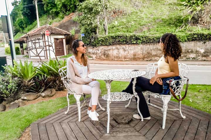 Imagem de duas mulher sentada em uma mesinha branca descontraídas em Domingos Martins