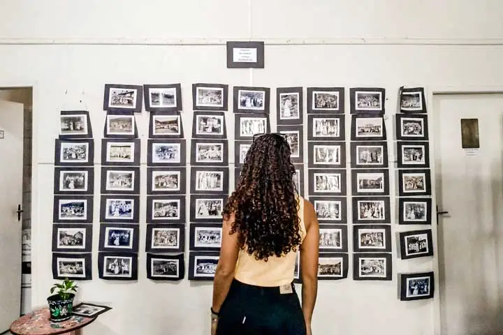 Imagem de uma mulher olhando um painel de fotos antigas que retratam a história da cidade de Domingos Martins
