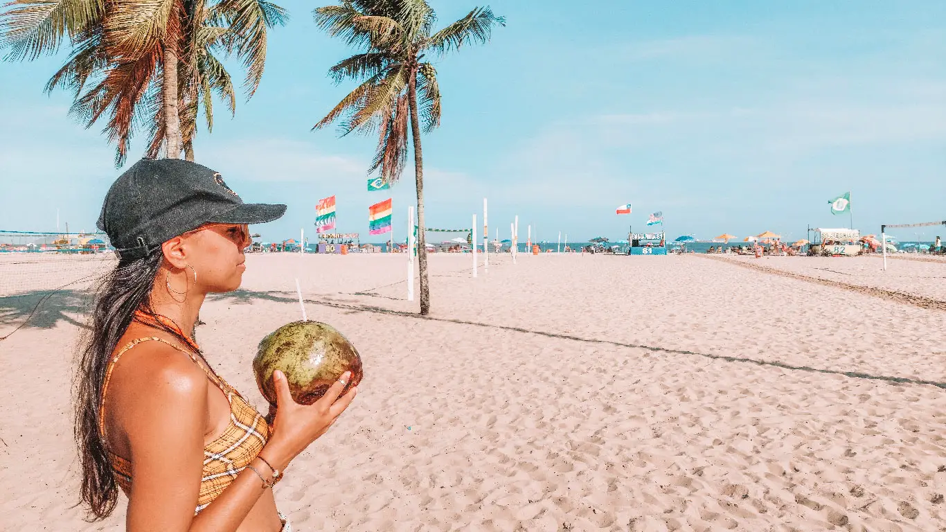Mulher tomando água de coco na Praia de Copacabana, uma das melhores para ficar no Rio de Janeiro.