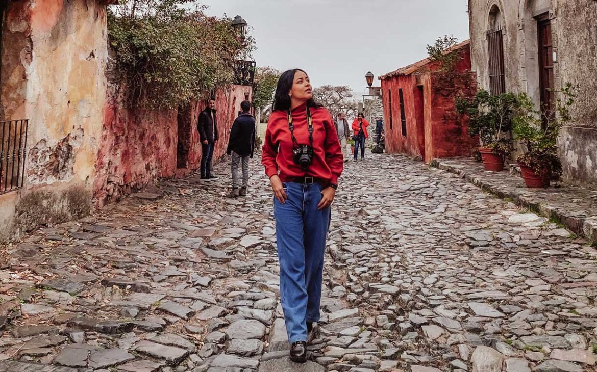 Uma mulher explorando a Calle de los Suspiros, uma atração imperdível para visitar em Colonia del Sacramento em um dia.