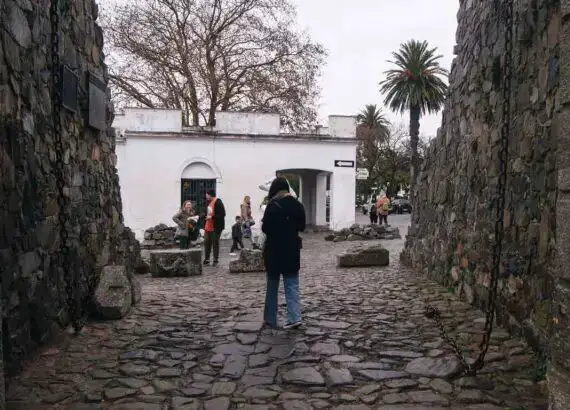 Mulher atravessando o Portón de Campo em Colonia del Sacramento com sua majestosa estrutura de pedras.