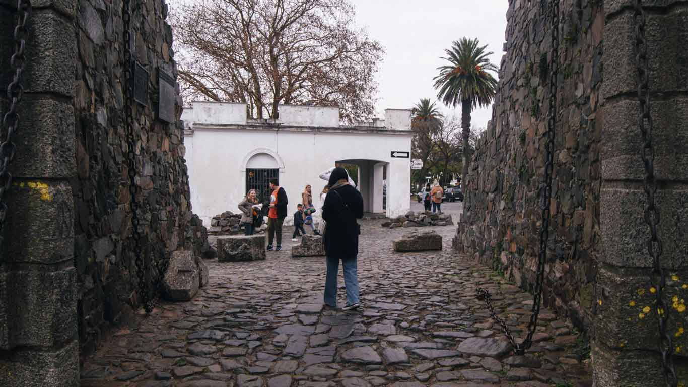 Mulher atravessando o Portón de Campo em Colonia del Sacramento.