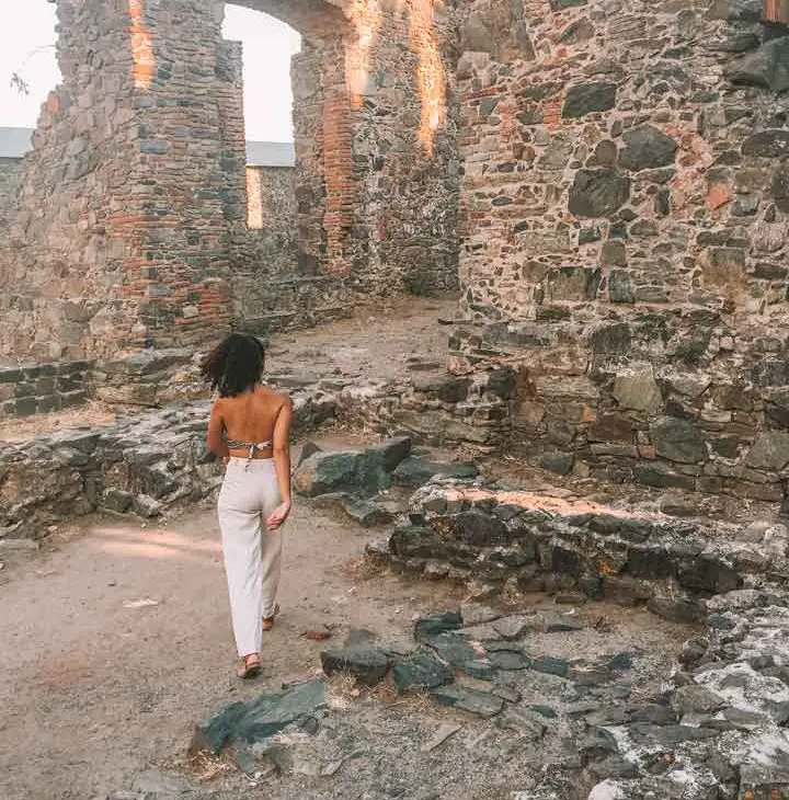Imagem de uma mulher caminhando entre as ruínas do Convento, situado aos pés do Farol.