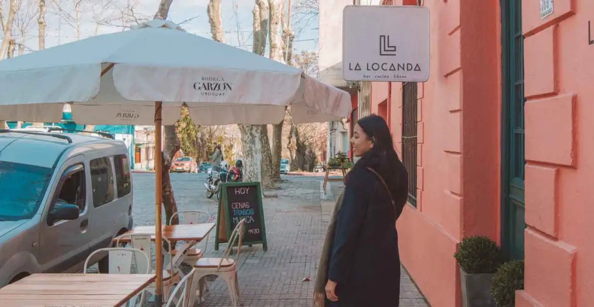 Mulher caminhando em frente ao restaurante La Locanda, uma excelente opção de onde comer em Colonia del Sacramento.