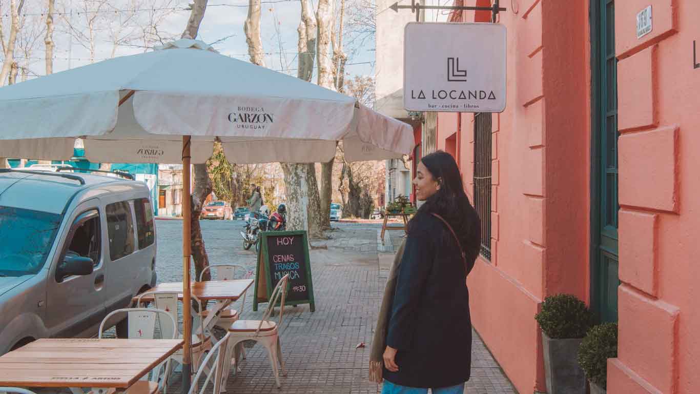 Mulher caminhando em frente ao restaurante La Locanda, uma excelente opção de onde comer em Colonia del Sacramento.