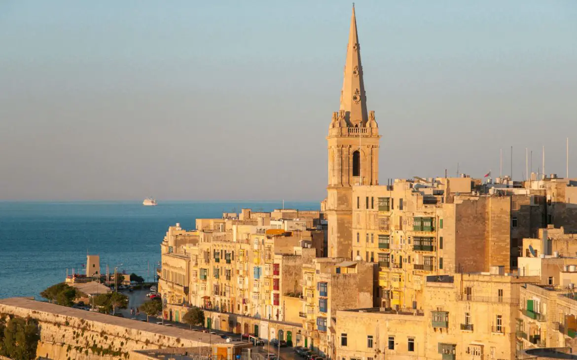 As casas e fortalezas muradas de Valletta, Malta, se erguem majestosamente, enquanto o azul sereno do mar se perde no horizonte distante.